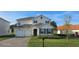 Charming two-story home showcasing a well-manicured lawn, brick driveway, and two-car garage, set against a blue sky at 18410 Blue Heron Cir, Deer Island, FL 32778
