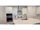 Modern kitchen with stainless steel appliances, white cabinetry, a large island with bar stools, and stylish fixtures at 18410 Blue Heron Cir, Deer Island, FL 32778