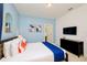 Bedroom painted in blue with abstract artwork and a dresser beneath the mounted TV at 2555 Shanti Dr, Kissimmee, FL 34746