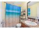 Cozy bathroom featuring a shower with a beach-themed curtain, vanity with decorative countertop, and ample storage space at 2665 Rotherham Rd, Tavares, FL 32778