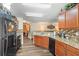 A view of the kitchen featuring wood cabinetry, mosaic backsplash, and a view to the living room at 2665 Rotherham Rd, Tavares, FL 32778