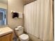 Bathroom featuring a wooden cabinet, a toilet with a white seat cover, and a shower with a white curtain at 2706 Bushman Dr, Kissimmee, FL 34746