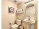 Bathroom featuring a pedestal sink, a round mirror, and a toilet with an art piece on the wall at 2706 Bushman Dr, Kissimmee, FL 34746