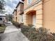 Townhouse exterior featuring an arched porch, a tan exterior, and street parking along the road at 2706 Bushman Dr, Kissimmee, FL 34746