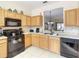 Functional kitchen with oak cabinets, black appliances, and tile floors for a clean and welcoming space at 2706 Bushman Dr, Kissimmee, FL 34746