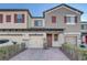 Charming townhome showcasing a brick driveway, stone accents, and a stylish red front door and shutters at 2725 Econ Landing Blvd, Orlando, FL 32825
