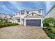 Exterior elevation showcasing a two-story home with gray shutters, a well-kept lawn, and a two-car garage at 280 Burma St, Kissimmee, FL 34747