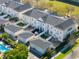 Aerial view of townhomes featuring dark rooftops, individual garages, and green spaces, including a shared pool at 2979 Upper Park Rd, Orlando, FL 32814