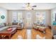 Bright living room featuring a gray couch, hardwood floors, and natural light from shuttered windows at 2979 Upper Park Rd, Orlando, FL 32814