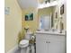 Cozy half-bathroom with vanity, framed mirror, neutral tile, and artwork of peaceful palms at 3114 Meleto Blvd, New Smyrna Beach, FL 32168
