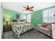 Relaxing bedroom featuring a tropical-themed bed, ceiling fan, and a comfortable lounge chair at 3114 Meleto Blvd, New Smyrna Beach, FL 32168