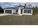 Charming home featuring a gray roof, gray garage door, modern front door, and a well-manicured lawn at 3519 Sw 131St Place St, Ocala, FL 34473