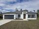 Charming home featuring a gray roof, gray garage door, modern front door, and a well-manicured lawn at 3519 Sw 131St Place St, Ocala, FL 34473