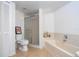Bathroom with a bathtub and glass-enclosed shower, neutral tile floor, and framed artwork at 5258 Tunbridge Wells Ln # 1902, Orlando, FL 32812