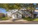 Exterior of attached villas with garages and mature trees providing shade on a sunny day at 5258 Tunbridge Wells Ln # 1902, Orlando, FL 32812