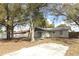 An exterior of a home's backyard with mature trees, a concrete patio, and a privacy fence at 558 Tyler Ave, Deltona, FL 32725