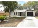 Charming single-story home with a well-manicured front yard, stone accents, and a black garage door at 558 Tyler Ave, Deltona, FL 32725