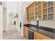 A bar area featuring a beverage refrigerator, sink, and upper cabinets with glass pane doors at 6005 Bancroft Blvd, Orlando, FL 32833