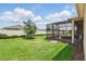 A spacious backyard with a screened lanai, lush green grass, a young tree, and a privacy fence at 6117 Sandy Springs Ct, St Cloud, FL 34771