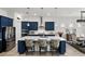 A modern kitchen features custom blue cabinets, stainless appliances, and a spacious center island with seating at 6117 Sandy Springs Ct, St Cloud, FL 34771