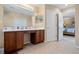 A bathroom featuring double sinks, a large mirror, tiled floors, and a view of the bedroom at 901 Dorset Pl, Davenport, FL 33896