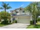 Lovely exterior featuring a two-car garage with a well-manicured lawn and verdant trees at 901 Dorset Pl, Davenport, FL 33896