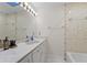 Bright bathroom with a shower-tub combo, a marble sink top and cabinets, and a large mirror with vanity lights at 109 Sweetwater Oaks Ln, Daytona Beach, FL 32114