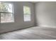 Bright bedroom features wood look floors, base molding, with a pair of windows overlooking the outdoors at 13215 Sw 41St Ct, Ocala, FL 34473