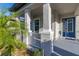 Inviting covered porch featuring stylish gray columns, white railings, and a vibrant blue front door, enhancing curb appeal at 14602 Winter Stay Dr, Winter Garden, FL 34787