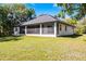 Back exterior view of home with screened in patio, and lush lawn and trees at 1475 Warrior Trl, Enterprise, FL 32725