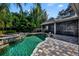 Beautiful pool with lush greenery, stone accents, and a covered patio for entertaining and relaxation at 1741 Pine Ave, Winter Park, FL 32789