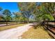 Long driveway leading to a house, bordered by a wooden fence and green fields at 20773 Starry St, Orlando, FL 32833