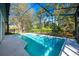 Screened-in pool area showing a backyard view of mature trees and a wooden fence, providing a private swimming space at 20773 Starry St, Orlando, FL 32833