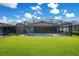 Expansive backyard showcasing a sparkling pool, screened enclosure, and lush green lawn at 2348 Victoria Dr, Davenport, FL 33837