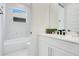 Bright bathroom featuring a white tub and shower combination, white cabinets, black hardware, and a large mirror at 2348 Victoria Dr, Davenport, FL 33837
