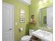 Charming powder room with a modern vanity, decorative mirror, and fresh green walls at 2724 Sarzana Ln, Apopka, FL 32712