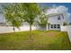 Landscaped back yard featuring a white vinyl fence, grass, and trees at 3010 Ballad Rd, Kissimmee, FL 34746