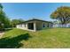 Back of the house with green lawn, sliding glass doors to the patio and mature trees in the background at 4198 Sw 128Th Pl, Ocala, FL 34473