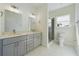 Bright bathroom with double vanity, grey cabinetry, glass enclosed shower and tile flooring at 4914 Sw 147Th Loop, Ocala, FL 34473