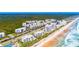 An elevated view of beachfront condos, and pristine shoreline along the ocean with lush greenery nearby at 5300 S Atlantic Ave # 7-301, New Smyrna Beach, FL 32169