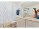 Well lit bathroom featuring a shower, toilet, and single sink vanity with storage and decorative mirror at 5300 S Atlantic Ave # 7-301, New Smyrna Beach, FL 32169