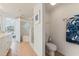 Well-lit bathroom with a toilet, shower, and tub, leading to the bedroom with tub and glass-block accent at 5300 S Atlantic Ave # 7-301, New Smyrna Beach, FL 32169