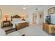 Bright bedroom with a ceiling fan, neutral carpet, television, decorative wood headboard, and an adjacent bathroom at 5300 S Atlantic Ave # 7-301, New Smyrna Beach, FL 32169