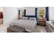 Bedroom featuring a queen bed with striped bedding and two windows with blue curtains at 600 Bullrush Ct, Davenport, FL 33837