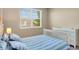 Well-lit bedroom with blue striped bedding, view of the outside, and beige walls at 8321 Bryce Canyon Ave, Windermere, FL 34786