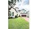 Inviting two-story home with a cylindrical tower, dark garage door, and lush green lawn at 9207 Busaco Park Way, Winter Garden, FL 34787