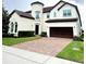 Elegant two-story home featuring a cylindrical tower, brick driveway, and well-manicured landscaping at 9207 Busaco Park Way, Winter Garden, FL 34787