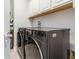Modern laundry room equipped with side by side washer and dryer and overhead cabinetry at 985 Huntspoint St, Winter Garden, FL 34787