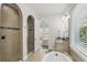 Bright bathroom featuring an arched shower with tan tile and granite countertops at 1377 Tappie Toorie Cir, Lake Mary, FL 32746