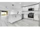 Modern kitchen features stainless steel appliances, white cabinets, an island with seating, and stylish light fixtures at 150 Chicago Woods Cir, Orlando, FL 32824